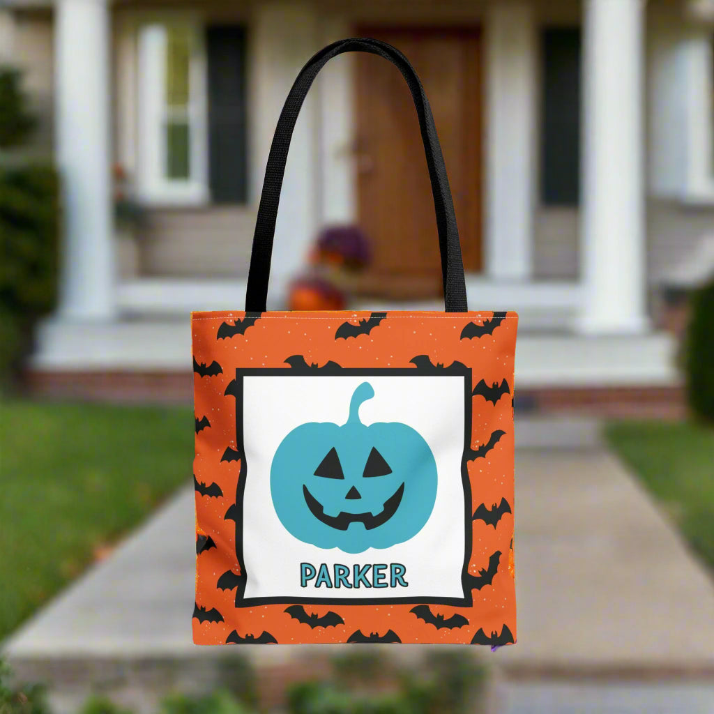 Halloween-themed tote bag with a blue pumpkin design and text, placed on a porch.