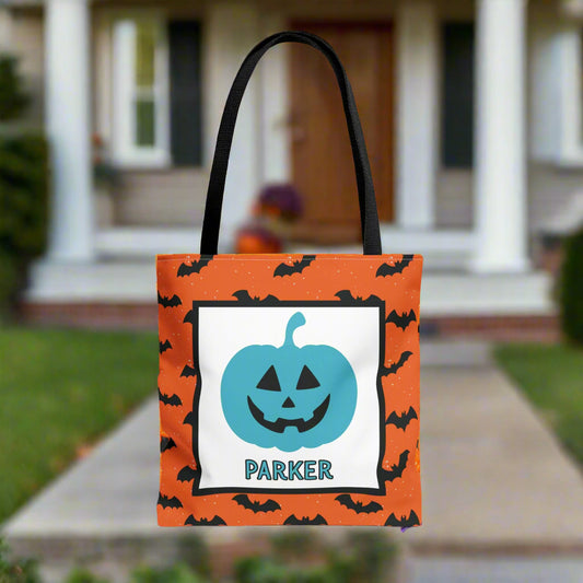 Halloween-themed tote bag with a blue pumpkin design and text, placed on a porch.