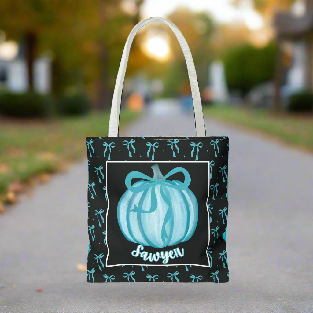 Tote bag with pumpkin design and  text on a teal bow background.
