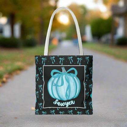 Tote bag with pumpkin design and  text on a teal bow background.