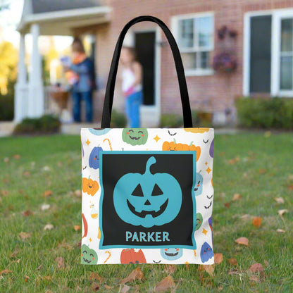 Halloween-themed tote bag with a pumpkin design and text, on a blurred background.