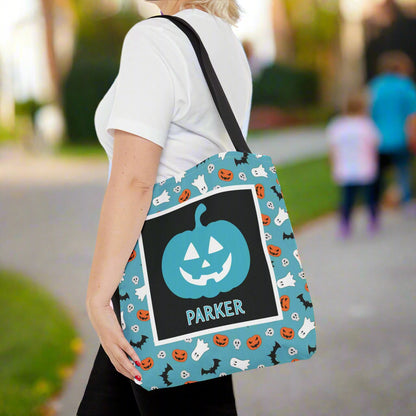 Person holding a Halloween-themed tote bag with a pumpkin design and a name.