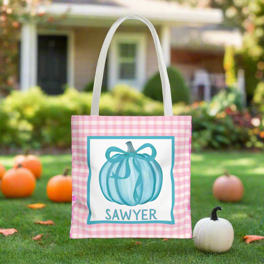 Tote bag with a blue pumpkin design and text on a Halloween-themed bakground.