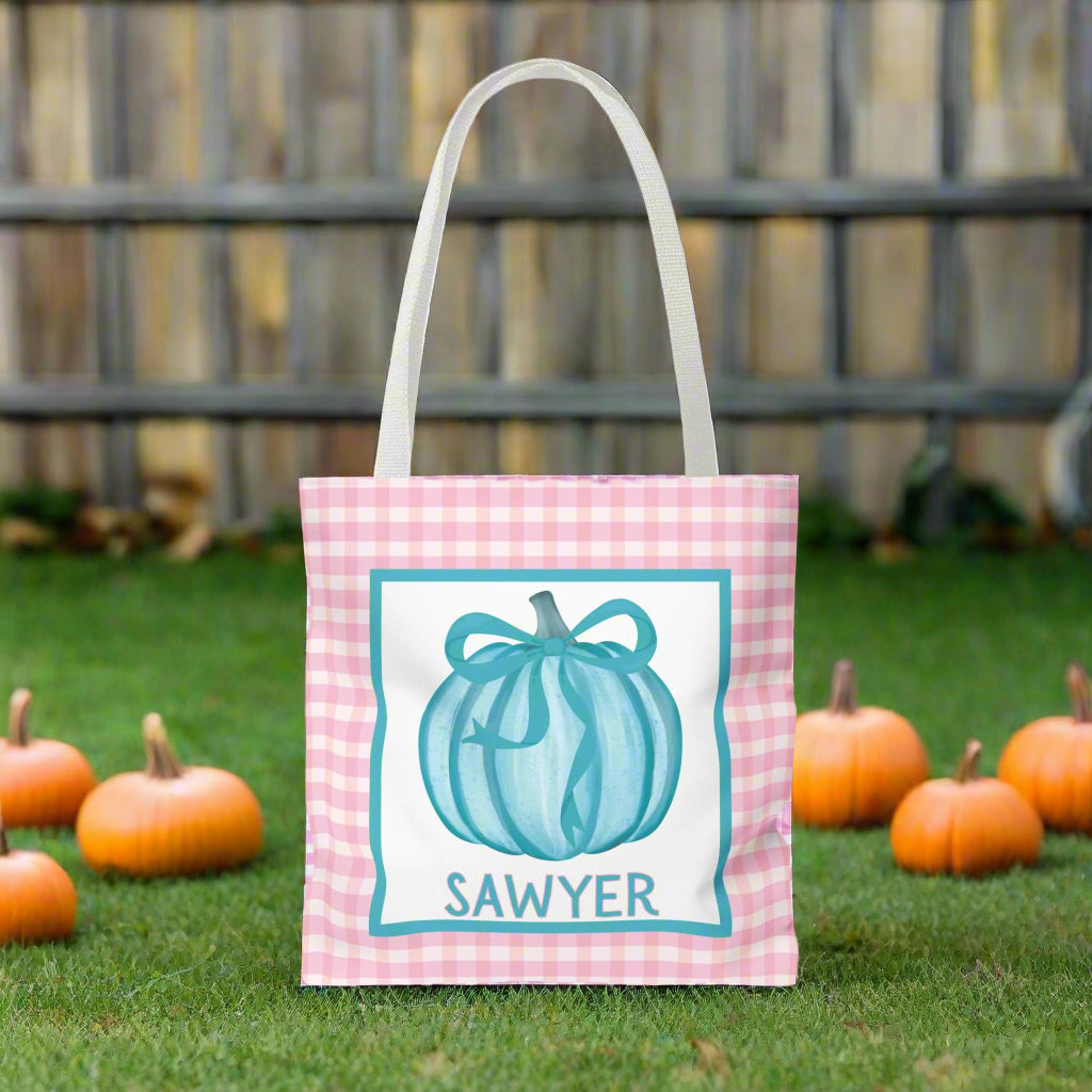 Tote bag with a teal pumpkin design and text on a pink check background.
