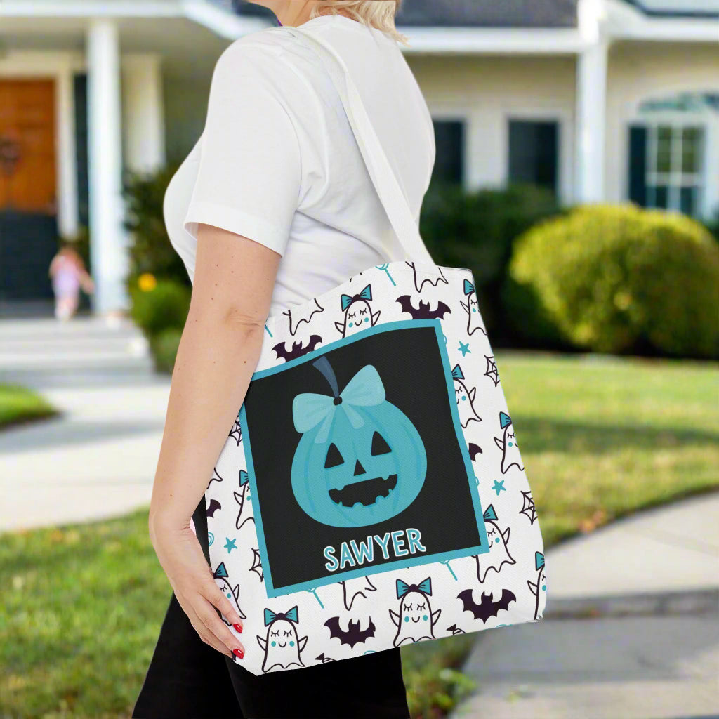Person holding a Halloween-themed tote bag with bats and ghosts with teal bows.