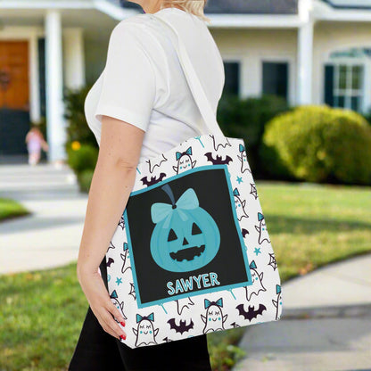 Person holding a Halloween-themed tote bag with bats and ghosts with teal bows.